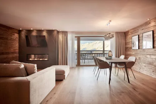Alpines Wohnzimmer mit Tisch und Kamin im TOP Hotel Hochgurgl