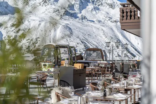 Restaurant mit Tischen und Stühlen vor einem Berg bei Promontoria Hochgurgl - TOP Hotel Hochgurgl