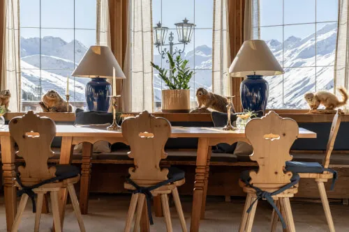 Room with table and chairs and a window overlooking snow-covered mountains - TOP Hotel Hochgurgl