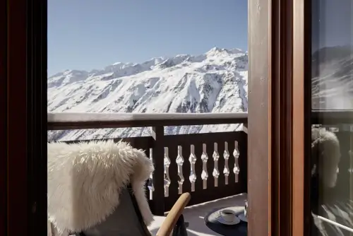 Blick vom Balkon des TOP Hotel Hochgurgl auf schneebedeckte Berge mit einer Tasse Kaffee.