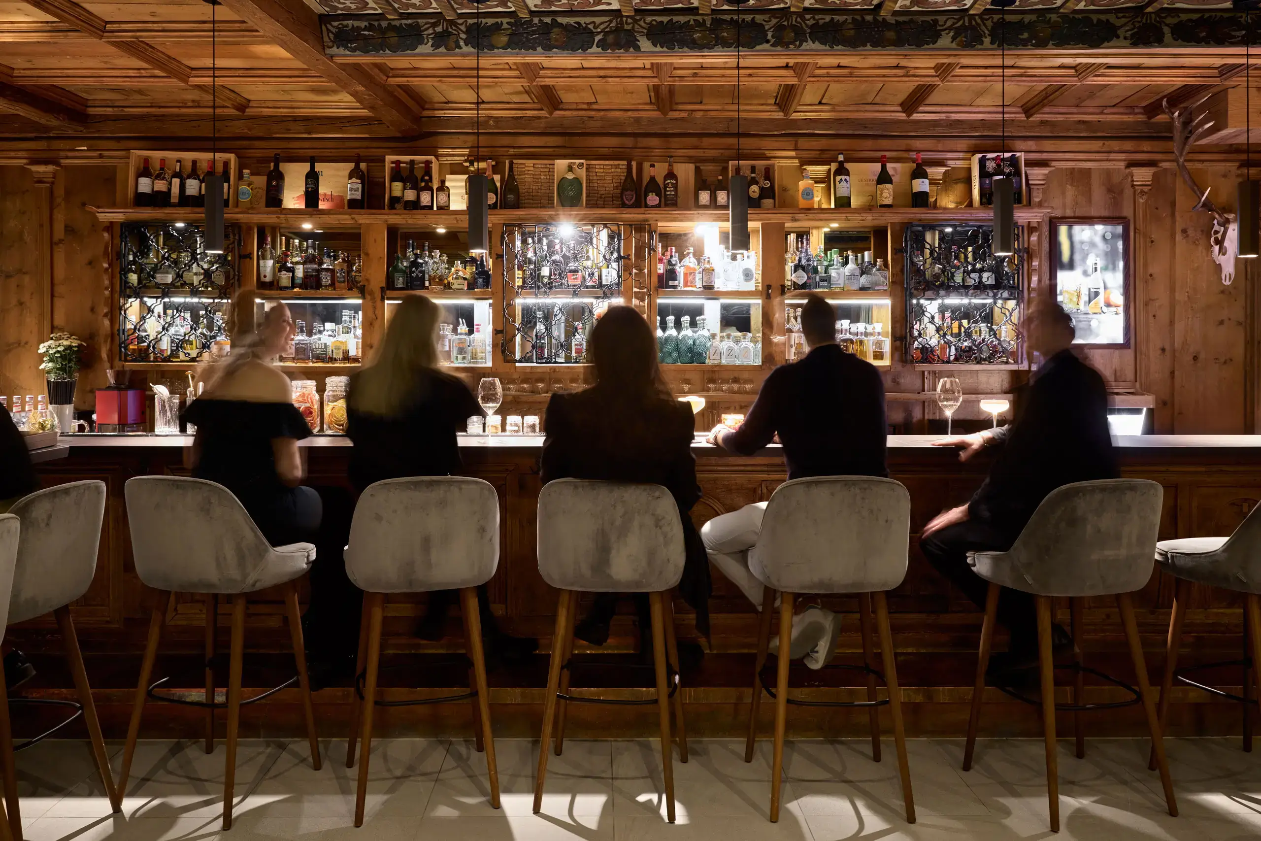 Guests seated at the bar in TOP Hotel Hochgurgl's restaurant with a cozy alpine wooden interior.