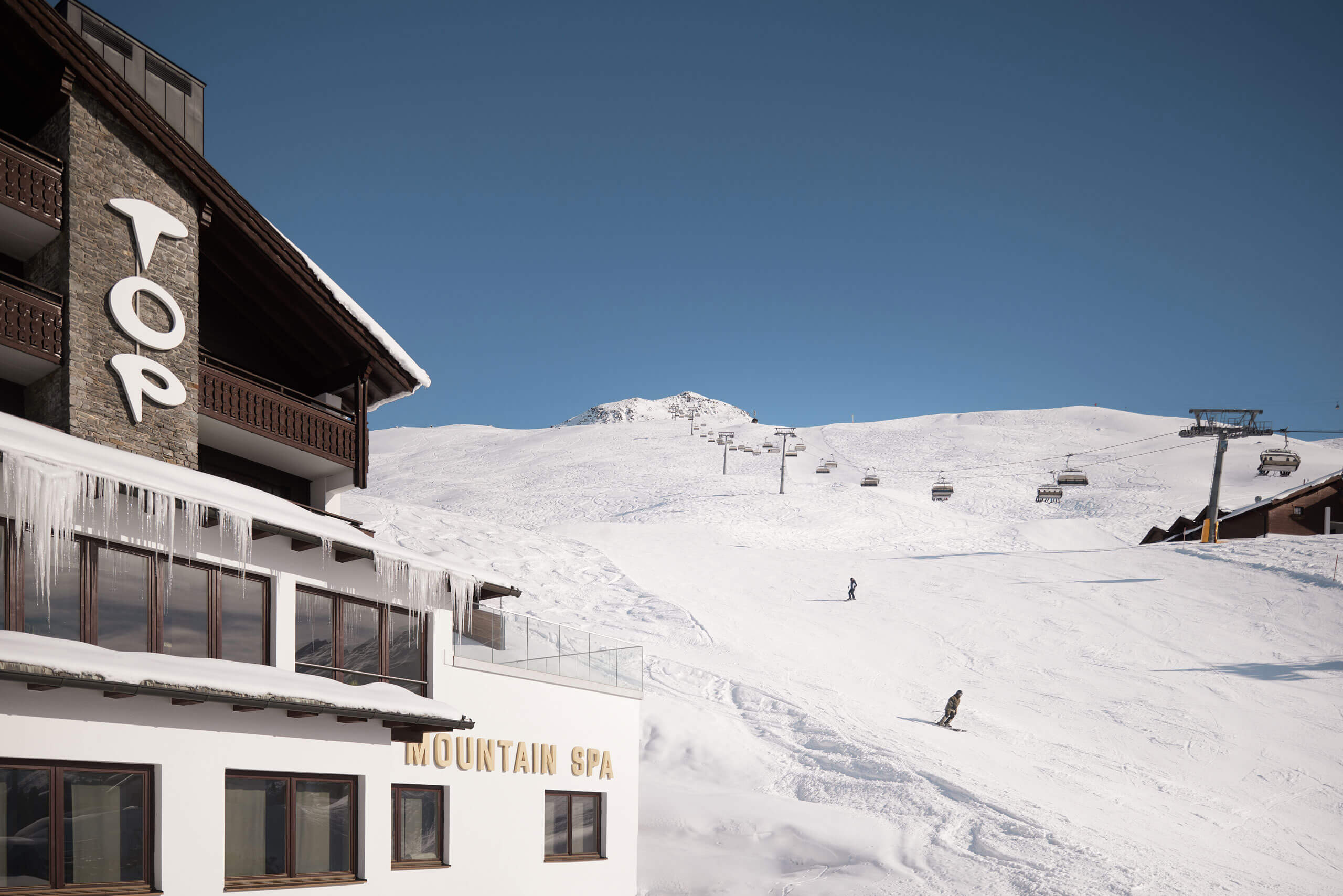 A building with a ski lift and a snow-covered mountain
