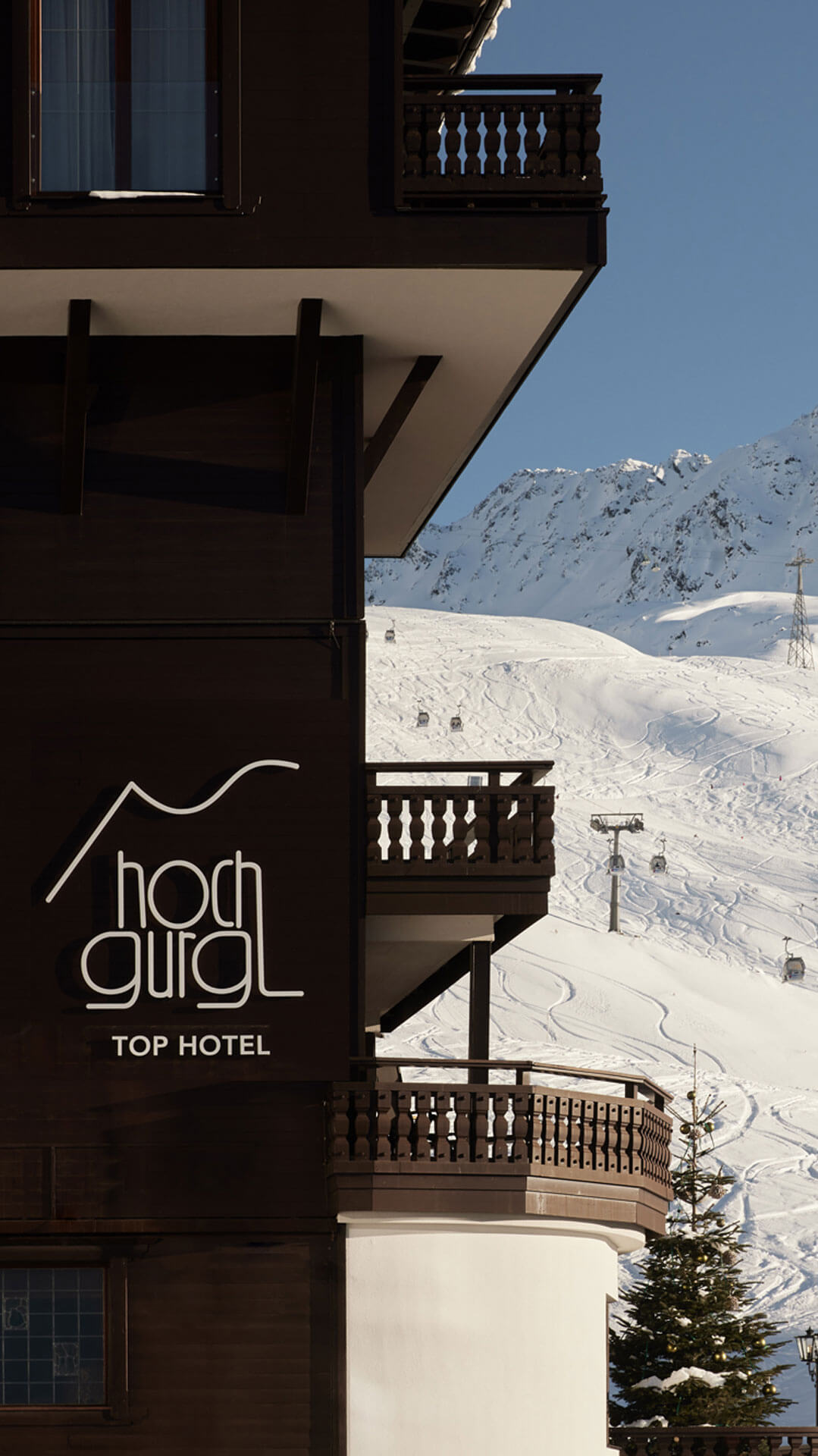 Ein Gebäude mit einem Balkon und einem Skilift im Hintergrund im TOP Hotel Hochgurgl