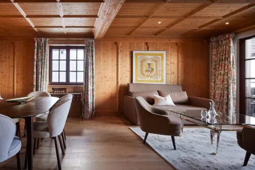 Ein gemütlicher Raum mit einer bequemen Couch und einem stilvollen Couchtisch, natürliches Licht fällt durch die Fenster herein. Ein Bild im Zusammenhang mit dem TOP Hotel Hochgurgl, Promontoria Hochgurgl GmbH.