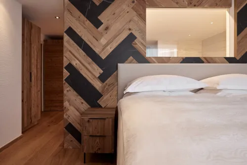 Ein gemütliches Bett mit einer Holzwand und einem Spiegel im Hintergrund in einem Zimmer im TOP Hotel Hochgurgl