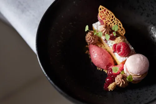 Buntes Dessert mit Himbeeren, Macaron und Himbeersorbet, kunstvoll angerichtet im TOP Hotel Hochgurgl.