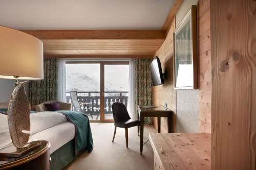 Cozy double room of approx. 25 - 35 m² at TOP Hotel Hochgurgl, featuring a comfortable bed, a chair, and a television
