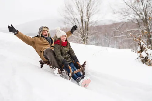 Familie fährt Schlitten im Schnee beim TOP Hotel Hochgurgl in Tirol.