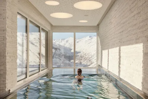 Person in pool at TOP Hotel Hochgurgl with mountain view, suitable for 2-4 guests.