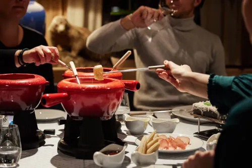 Gesellige Fondue-Erfahrung in der Murmelstube mit rotem Fonduetopf und köstlichen Beilagen.