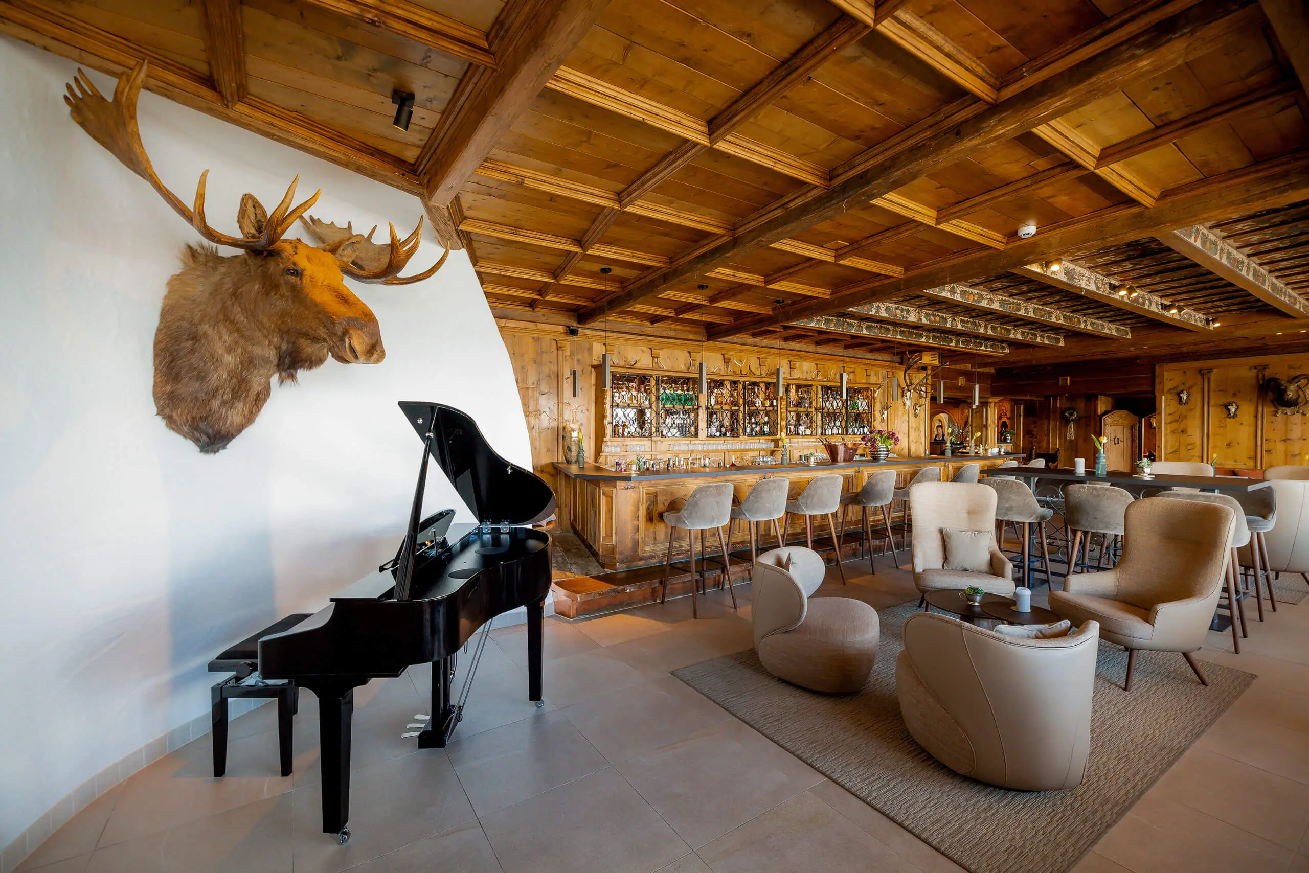 Luxuriöse Hotel-Lounge mit Bar, Flügel und Elchkopf im TOP Hotel Hochgurgl.