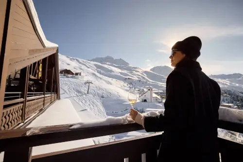 Frau mit Drink auf dem Balkon mit Blick auf die verschneiten Berge im TOP Hotel Hochgurgl.