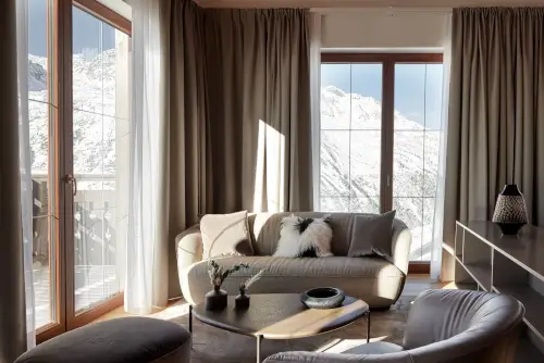 Luxuriöses Hotelzimmer mit Sofa und Blick auf die schneebedeckten Berge.