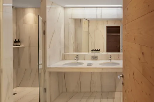 Ein luxuriöses Badezimmer mit Marmorwaschtischen und einer Glastürdusche im TOP Hotel Hochgurgl