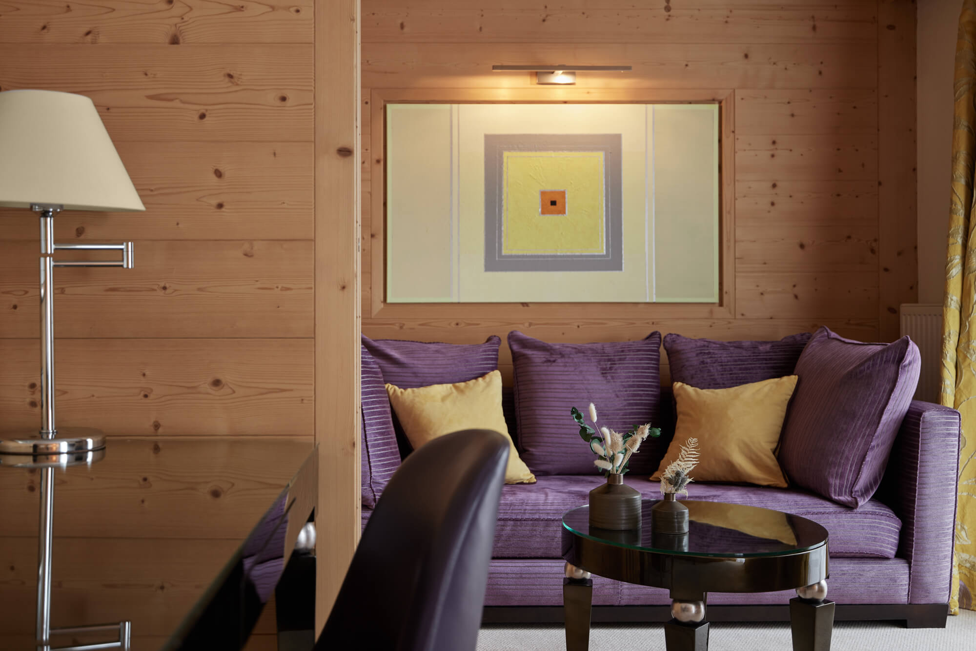 A purple couch with yellow pillows and a glass table in a stylish interior design setting