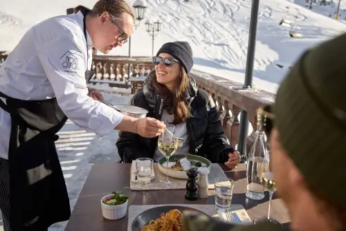 Koch serviert Gourmet-Essen im malerischen Restaurant des TOP Hotel Hochgurgl.