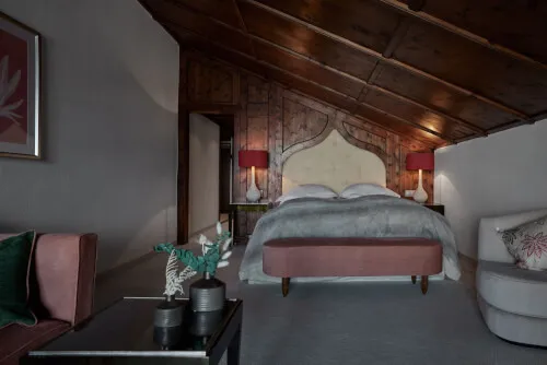 Ein stilvolles Schlafzimmer mit einem Bett und einer gemütlichen Bank in der Ecke im TOP Hotel Hochgurgl