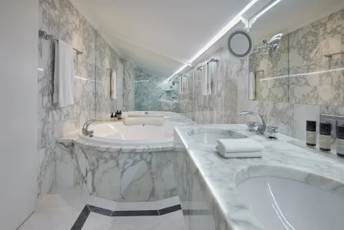 Ein luxuriöses Badezimmer mit Marmorwänden und einer atemberaubenden Badewanne im TOP Hotel Hochgurgl.