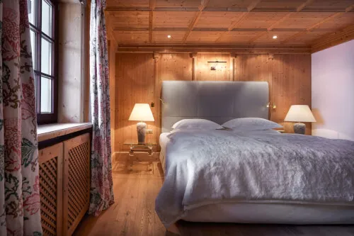 Gemütliches Doppelbett mit weißer Bettdecke und Lampe in einem 92 m² großen Zimmer, geeignet für 2-3 Personen im TOP Hotel Hochgurgl
