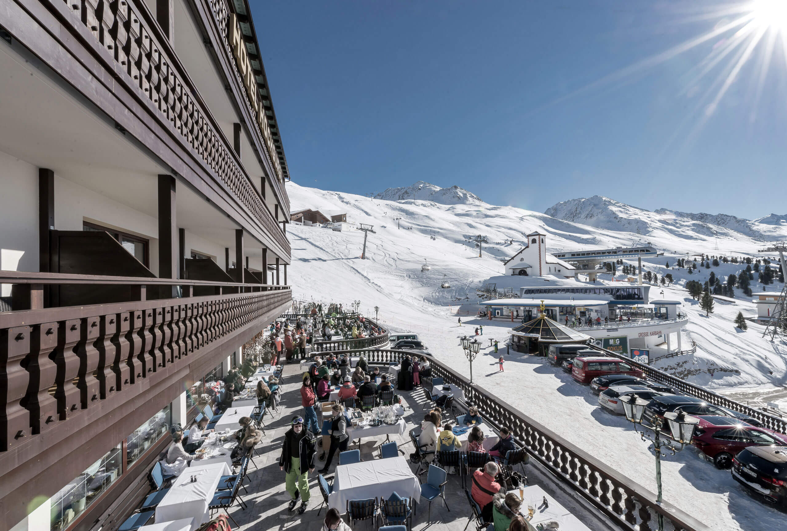 Menschen sitzen an Tischen und Stühlen auf einem verschneiten Berg in Hochgurgl. Der Skiurlaub begi