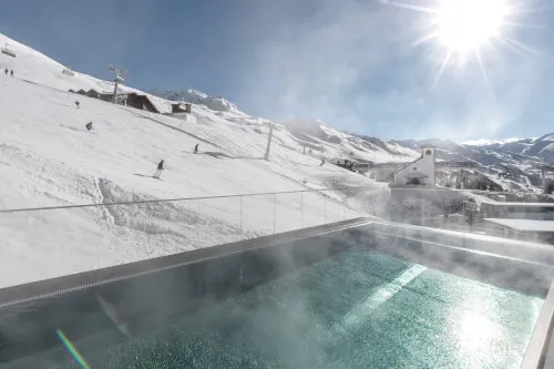 Beheizter Außenpool mit Blick auf verschneite Berge im TOP Hotel Hochgurgl.