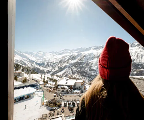 Frau blickt aus Fenster des TOP Hotel Hochgurgl auf verschneite Berge