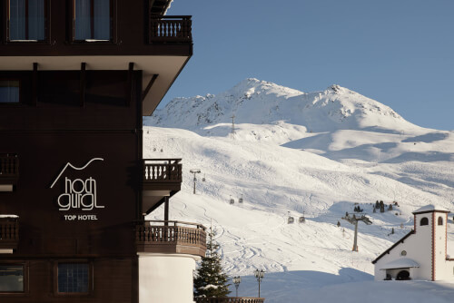 Promontoria Hochgurgl GmbH - TOP Hotel Hochgurgl: malerischer Blick auf das Hotel, den Skilift und die schneebedeckten Berge im Hintergrund, der das Wesen eines alpinen Winterresorts einfängt.