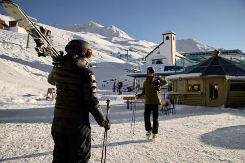 Zwei Skifahrer im TOP Hotel Hochgurgl, mit schneebedeckten Bergen und Skiliften im Hintergrund.