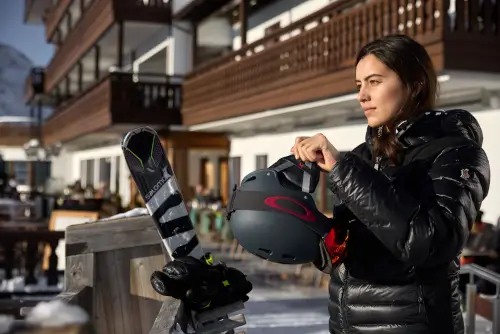 Eine Frau bereitet sich mit einem Helm und Skiern im TOP Hotel Hochgurgl auf das Skifahren vor.