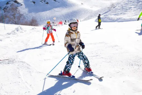 Kind, das in Hochgurgl auf einer schönen verschneiten Piste mit anderen Skifahrern fährt.