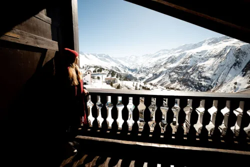 Blick vom Balkon im TOP Hotel Hochgurgl auf die verschneiten Berge und eine entspannte Person.