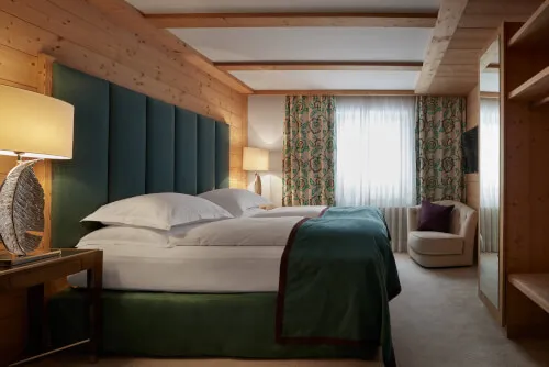 Gemütliches Doppelzimmer von 20 - 31 m² im TOP Hotel Hochgurgl, ausgestattet mit einem bequemen Doppelbett, Polsterstühlen und eleganter Inneneinrichtung