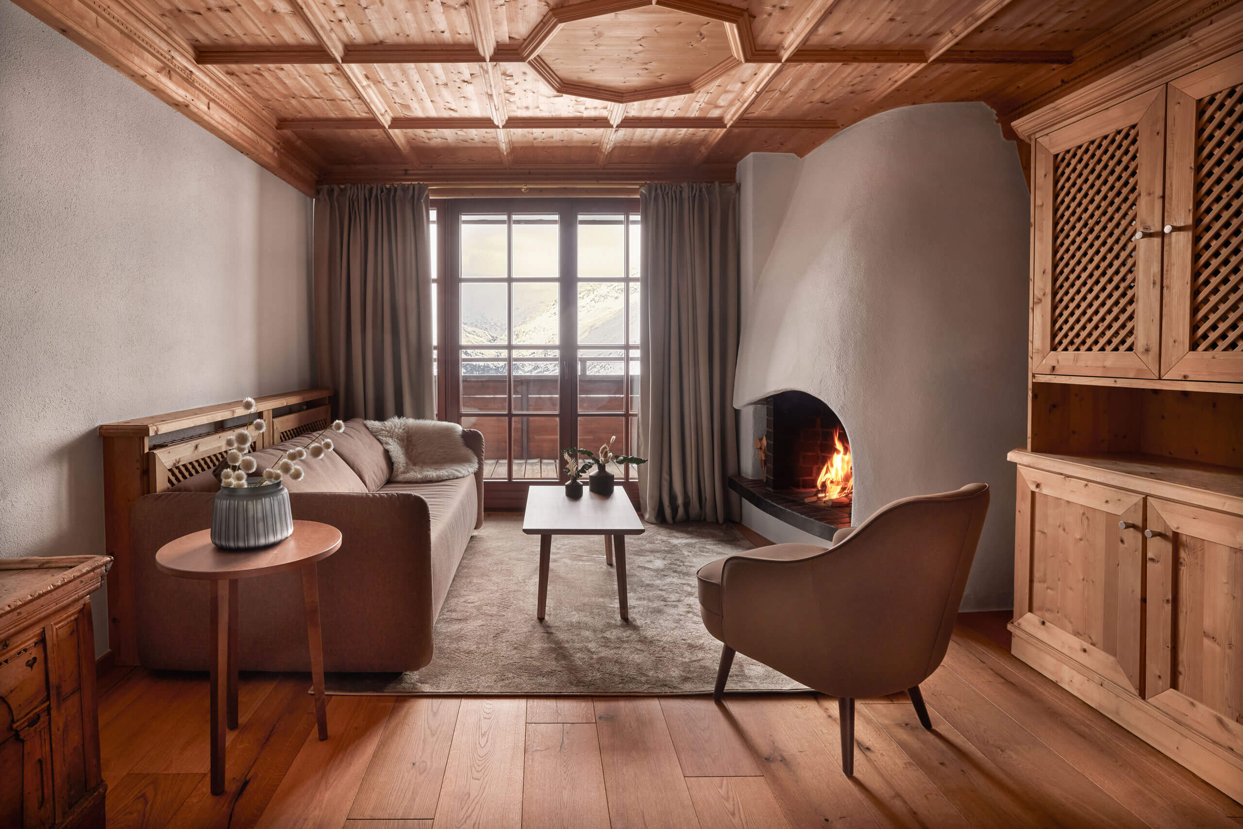 Ein Wohnzimmer mit Kamin und Couch in der Classic Suite Bergblick. Moderne alpine Eleganz prägt die