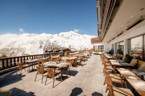 Outdoor-Terrasse des TOP Hotels Hochgurgl mit Blick auf die Berge und Esstischen.