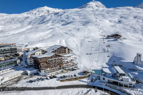 Blick auf das TOP Hotel Hochgurgl umgeben von einer schneebedeckten Landschaft und Skigebieten.