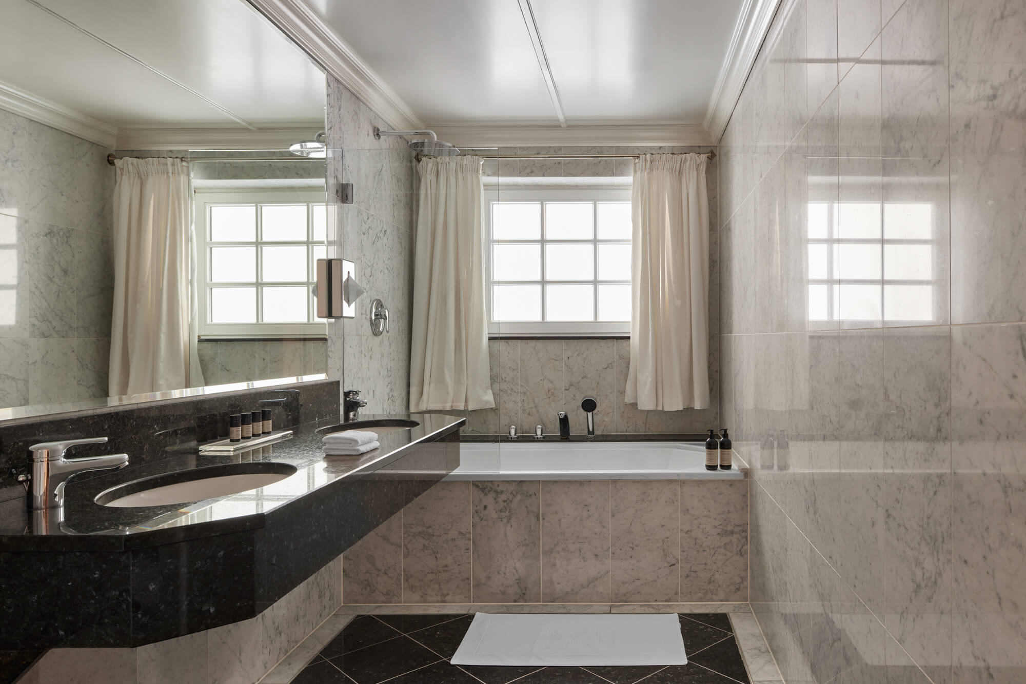Ein Badezimmer mit einer Marmor-Arbeitsplatte und einer Badewanne im TOP Hotel Hochgurgl