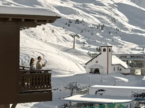 Paar im TOP Hotel Hochgurgl, das eine Winterlandschaft mit Schnee, einer Kirche und einer Seilbahn genießt.