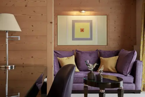 Stylischer Wohnbereich im TOP Hotel Hochgurgl mit lila Sofa und modernem Kunstwerk.